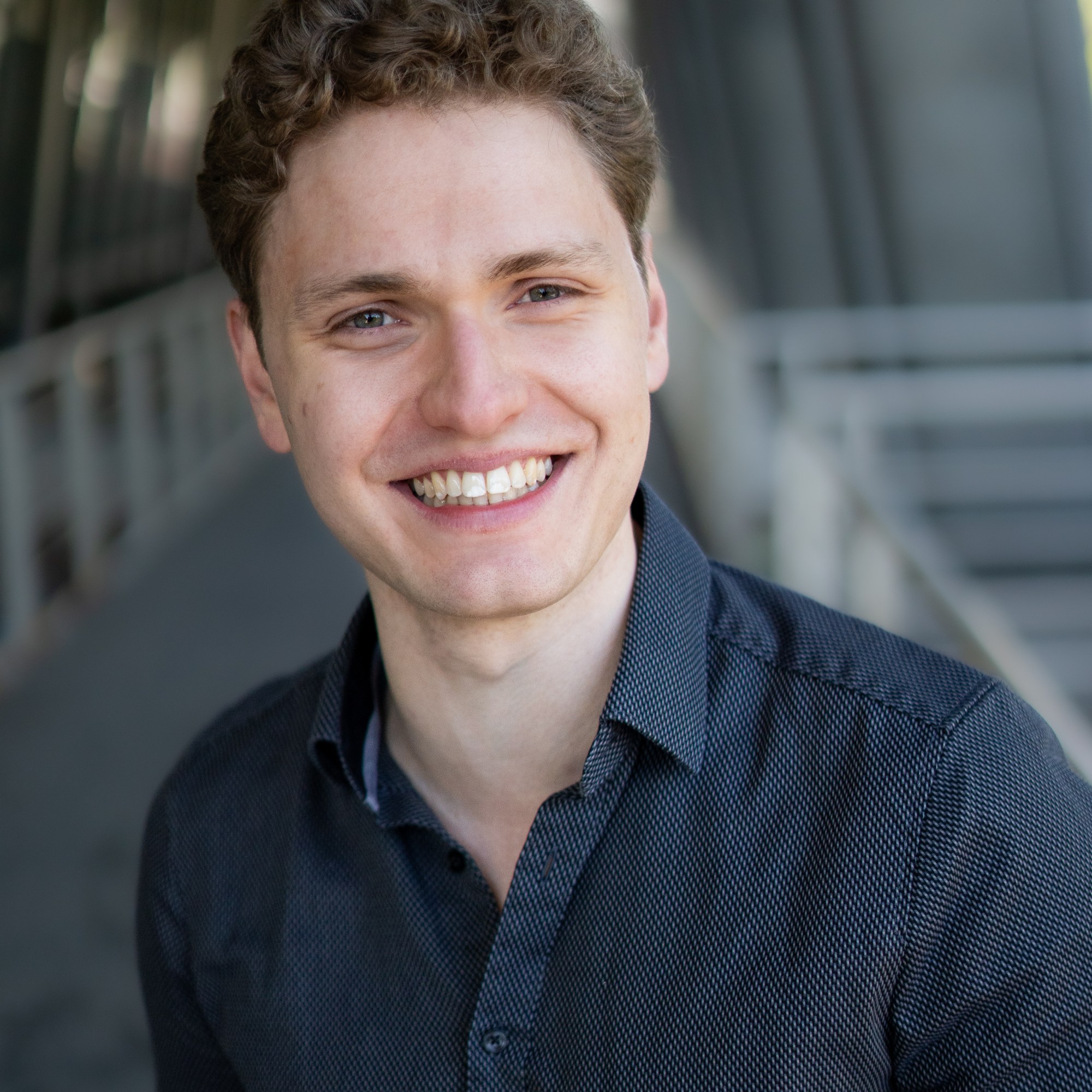 Lukas Baeskow Schauspieler Sänger lächelnd lachend graues Hemd Zähne zeigend