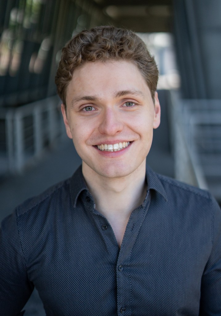 Lukas Baeskow lächelt mit Zähnen für den Headshot in die Kamera